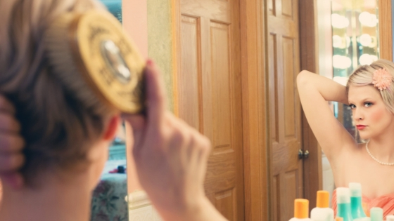 Woman looks in mirror while she brushes her hair.